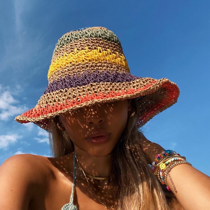 Der Hut zeigt ein einzigartiges gehäkeltes Design in einem klassischen Fischerhut-Stil, mit farbenfrohen Streifen um den Hut herum