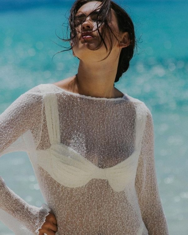 Modell im weißen Mesh-Kleid geniesst die Meeresbrise