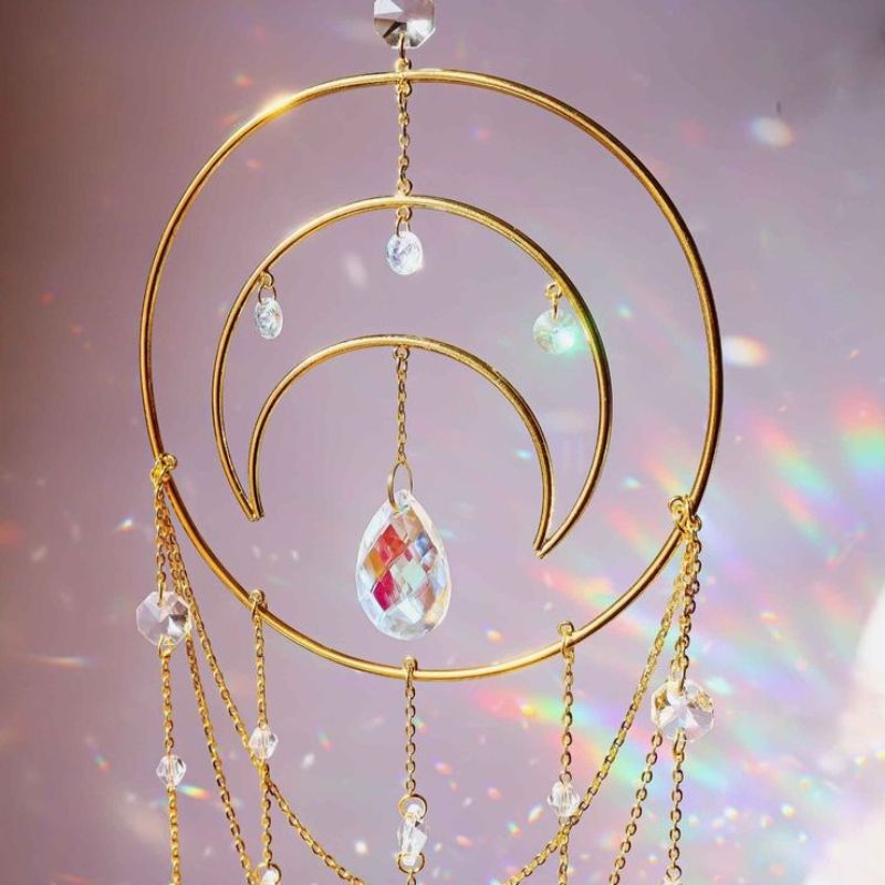 Goldener Suncatcher mit Halbmond Symbol und Kristallsteinen die das Sonnenlicht einfangen 