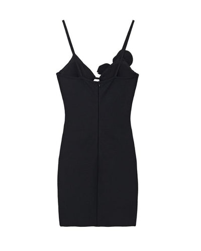 schwarzes Kleid mit Glitzer Blume ueber einer Brust 